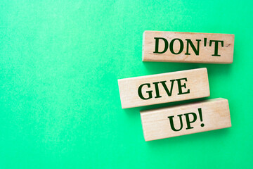 Don't give up words on wooden blocks on green background.