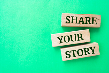 Share your story words on wooden blocks on green background.
