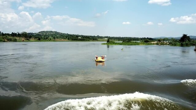 Drone front view of a yellow boat descending and capsizing at a waterfall on the Nile River in Jinja, Uganda.
