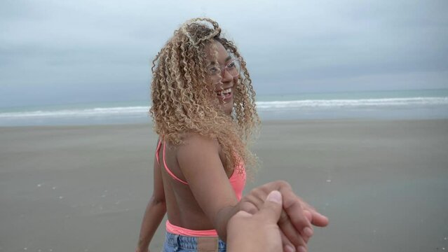 Latina with curls Walking on the beach in slow motion hand in hand with her husband.