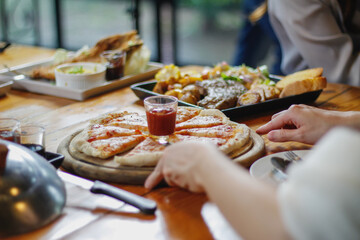A young woman is happy to see the food on the table and choose the pizza menu to eat with good...