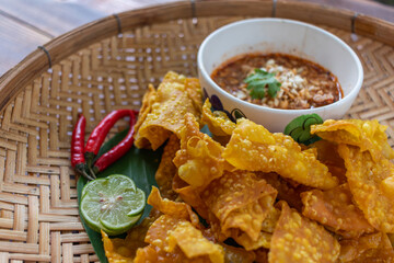 Crispy dumplings wrapped in chicken, vegetables and spices are served in a white plate placed on a wooden table inside the restaurant. Fried dumplings are popular for their delicious taste.