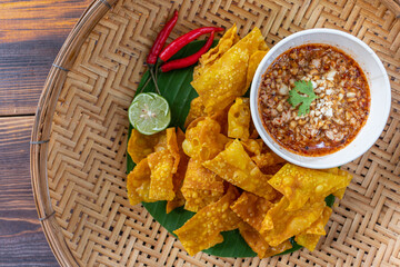 Crispy dumplings wrapped in chicken, vegetables and spices are served in a white plate placed on a wooden table inside the restaurant. Fried dumplings are popular for their delicious taste.