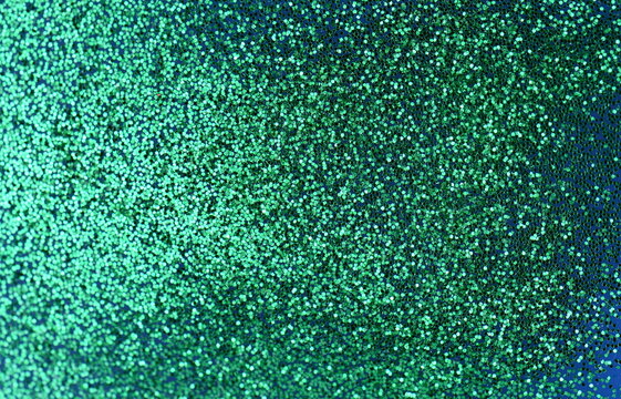 Green glitter on light background - macro photo. Green glitter surface with green light bokeh - It can be used for background for special occasions promotion campaign.