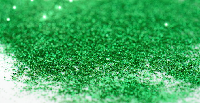 Green glitter on light background - macro photo. Green glitter surface with green light bokeh - It can be used for background for special occasions promotion campaign.