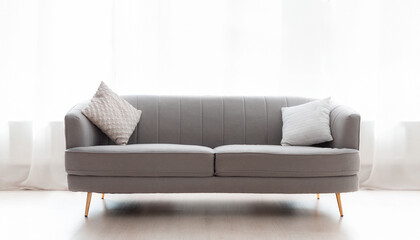 Minimalistic gray sofa with pillows on window backgrounds. Copy space. The concept of renovation of apartment and design interior