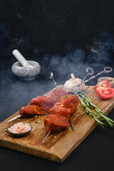 Smoky skewers with marinated raw pork meat on cutting board