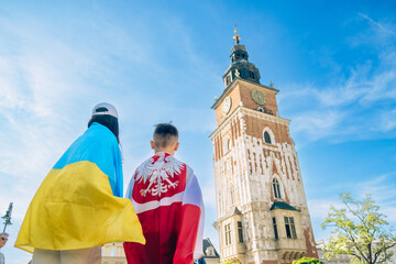 woman and little boy covered with ukraine and poland flag in city center