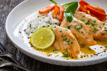 Fried chicken breasts in curry sauce with white rice on wooden table
