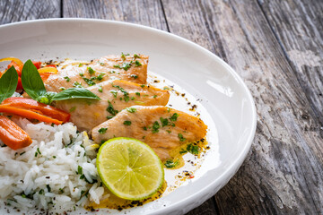 Fried chicken breasts in curry sauce with white rice on wooden table
