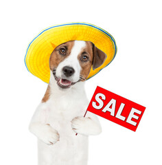 Jack russell terrier puppy wearing summer hat holds sales symbol. isolated on white background