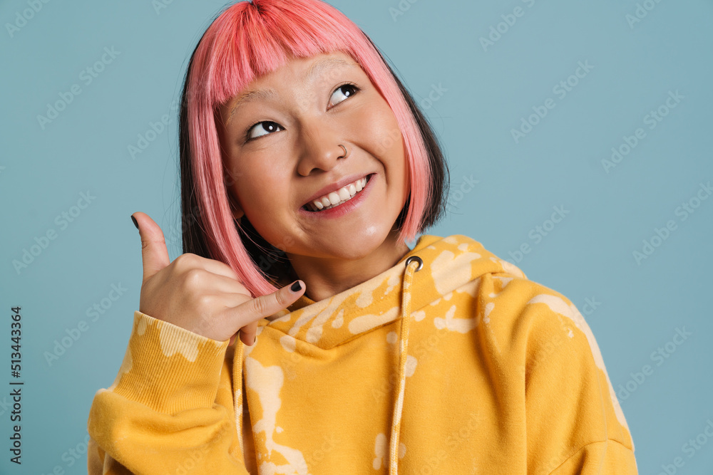 Wall mural asian girl with pink hair and piercing making handset gesture