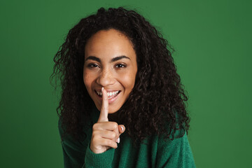 Young black woman smiling and making silence gesture - obrazy, fototapety, plakaty