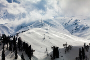 Gulmarg snow in the middle of Himalaya mountain at Kashmir. Snow against Sun light at Gulmarg village. Landscape of beautiful nature of Himalaya mountain at blue sky.