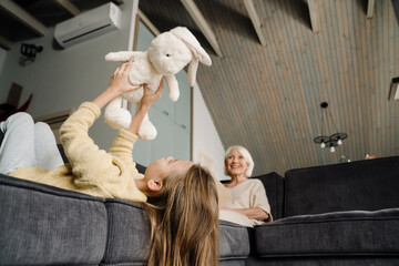 White girl playing with her toy while resting on couch