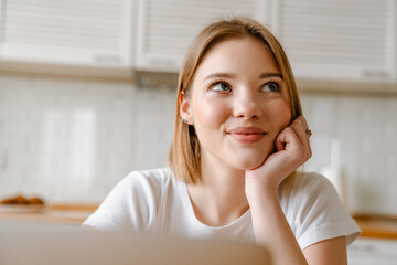 Naklejka premium Smiling young woman studying with laptop computer
