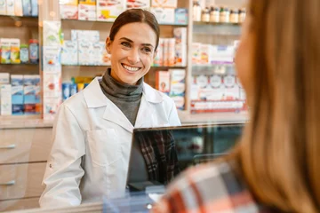 Foto auf Acrylglas Apotheke White apothecary wearing lab coat working with customer in pharmacy