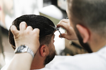 Fototapeta premium Male client getting haircut by hairdresser in barbershop