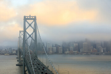 Fototapeta premium Foggy Sunset over San Francisco Bay Bridge and Waterfront via Yerba Buena Island.