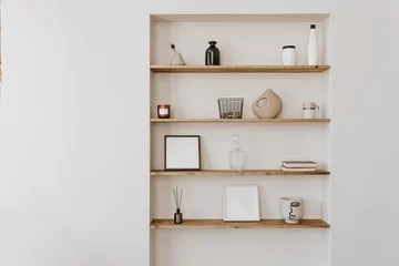 Fototapete Boho Decorated shelf on white wall. Aesthetic luxury minimalist home interior design decoration. Elegant Scandinavian, hygge style interior. Picture frames, fragrance, vase, books, candle  © Floral Deco