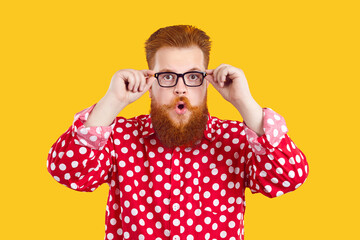 Fat chubby bearded redhead man in crazy funny shirt and cool stylish spectacles isolated on yellow...