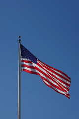 The United States flag waving high in the blue sky