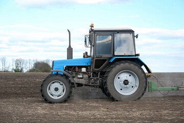 Tractor with planter cultivating field on sunny day. Agricultural industry