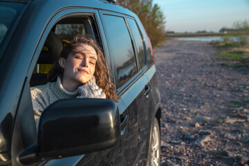 Smiling woman with eyes closed sitting in car
