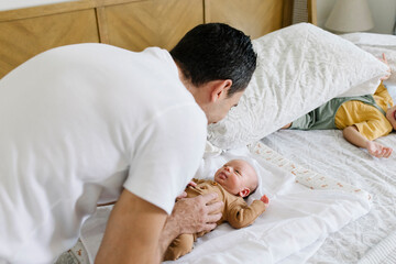 Smiling man playing with baby on bed at home
