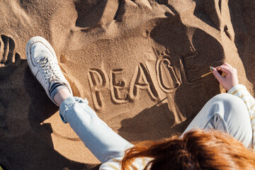 Woman writing peace on sand at beach