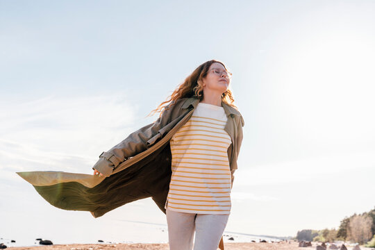 Woman with eyes closed walking at beach