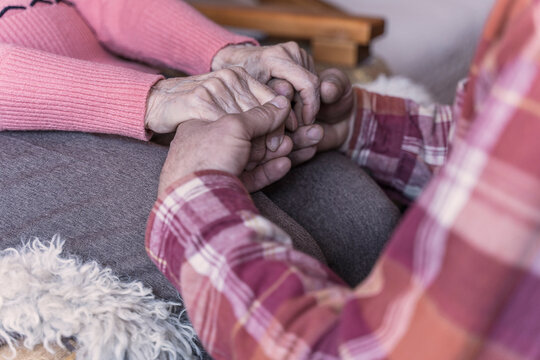 Man holding hands of senior woman at home