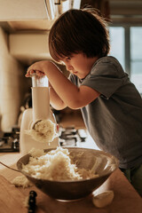 the boy helps his mother in the kitchen, the child rubs potatoes for potato pancakes in the kitchen