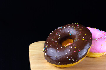 Close up Chocolate donut on a wooden board on black background.