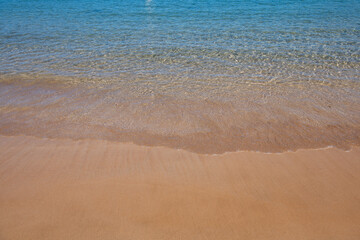 Fototapeta na wymiar Beach background. Calm beautiful ocean wave on sandy beach. Sea view from tropical sea beach.
