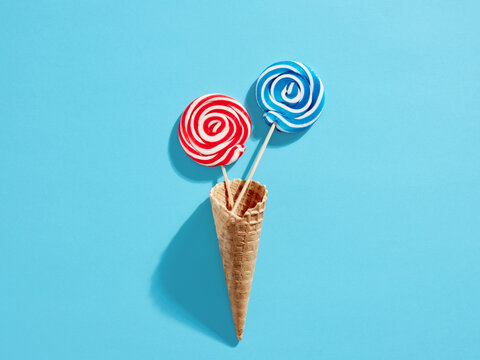 Colorful Swirl Round Candy Lollipops In Waffle Ice Cream Cone On Blue Background.