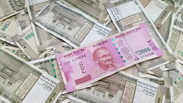 Two thousand rupee india currency bank paper note cash falling on table filled with heap of scattered five hundred notes. Loan, wealth, finance, savings, success, income, tax, money, rich concept.