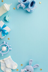 Baby concept. Top view vertical photo of giftbox shoes socks pacifier teether milk bottle knitted bunny rattle toy and gold stars on isolated pastel blue background with copyspace