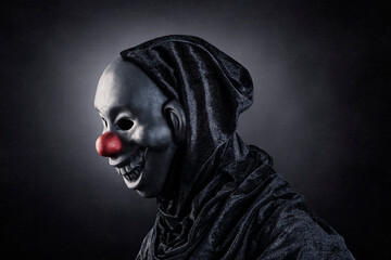 Scary clown showing his teeth over dark misty background