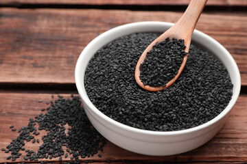 Bowl and spoon with black sesame on wooden table