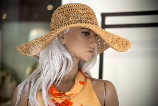 closeup of big summer hat and red dress on mannequin  in a fashion store showroom for women