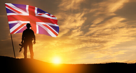 Silhouette of soldier with United Kingdom flag on background of sunset. Greeting card for Poppy...