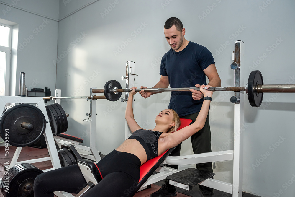 Wall mural female client and the trainer work out according to an individual program together in the gym