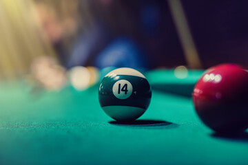 female hands in deftly holding a cue and trying to drive a billiard layer into the hole.