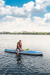 Fototapeta na wymiar young woman wear life vest paddle boarding on a lovely lake at summer hot day