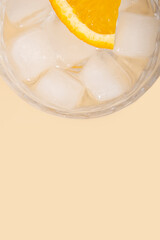 Cocktail with ice slice of orange on a beige background. Top view, flat lay