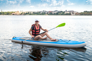  pumped-up athlete poses on the water on a board and catches the sun's rays on her body.
