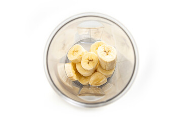 Banana cut into slices in a transparent container on a white background. Top view, flat lay
