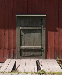 Green wood door on a 1700s red wood house a sunny summer day in Stockholm