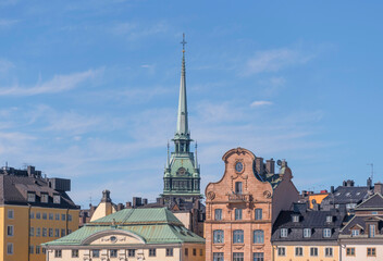 Facades, roofs, dorms and the church tower of the German church in the district Gamla Stan a sunny...